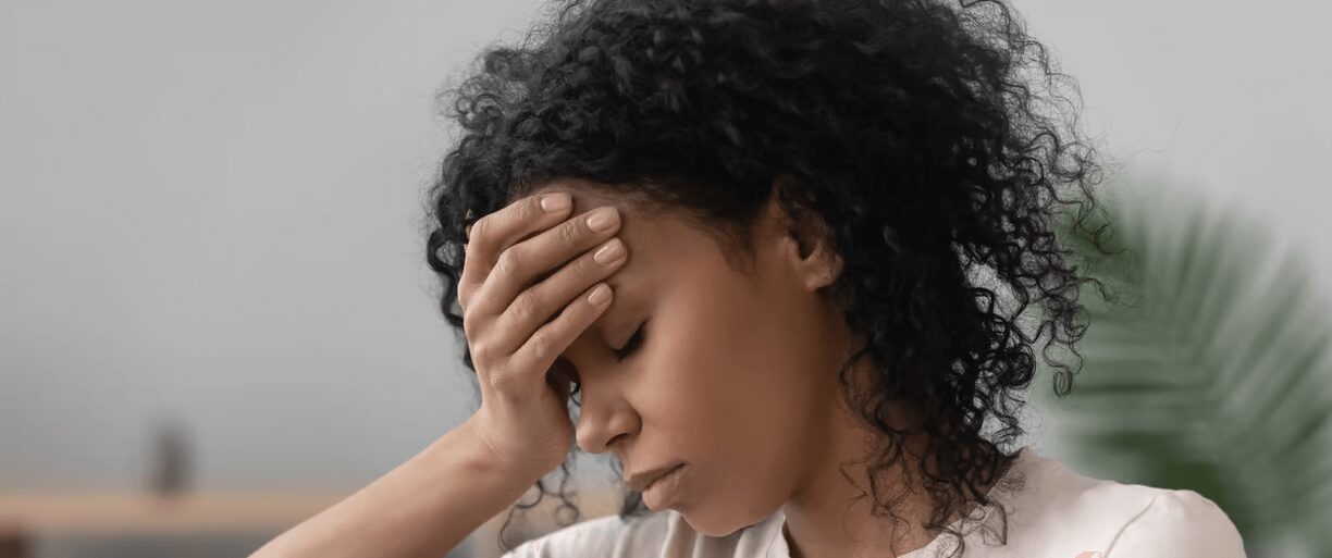 Woman with curly hair holding her head.